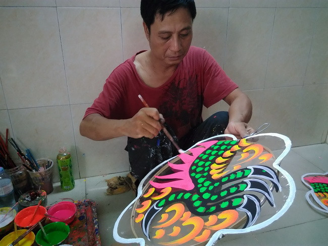 Anh Nguyễn Trọng Thành đang vẽ trang trí họa tiết cho chiếc lồng đèn hình con rồng