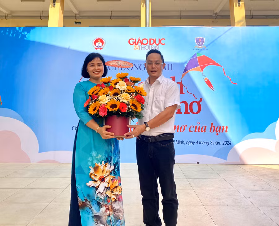 Nhà báo Nguyễn Anh Tú, Phó trưởng Cơ quan Thường trú Báo Giáo dục và Thời đại tại TP.HCM tặng hoa cho cô Hoàng Thị Hảo, Hiệu trưởng Trường THPT Đào Sơn Tây.