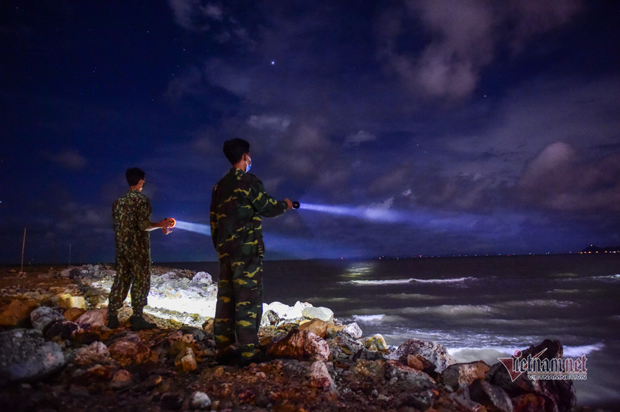 Các chiến sĩ dùng đèn pin quan sát các tàu cá trên biển