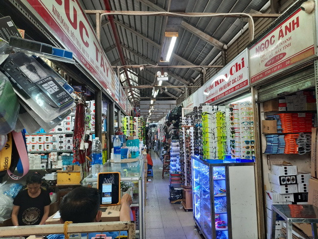 Lối vào bên trong chợ nhỏ hẹp là các gian hàng kinh doanh đồ điện tử, đồng hồ..