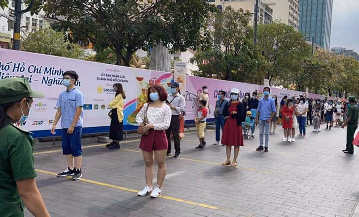 Du khách xếp hàng khi đến thăm quan đường hoa Nguyễn Huệ phải đeo khẩu trang và đo thân nhiệt ( Ảnh: BTC)
