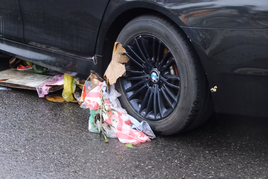 Rác theo dòng nước tấp vào xe bên đường.