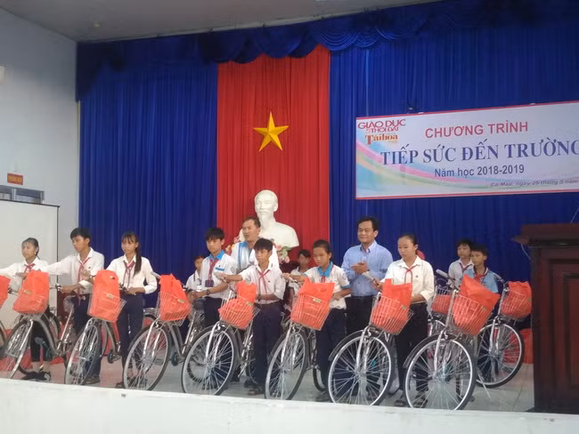 Ông Ngô Minh Toại - Phó Chủ tịch UBND huyện Ngọc Hiển (phải) cùng ông Nguyễn Văn Hậu - Ban Quản trị Hội bảo tồn lan rừng Việt Nam trao xe đạp và tập cho học sinh.