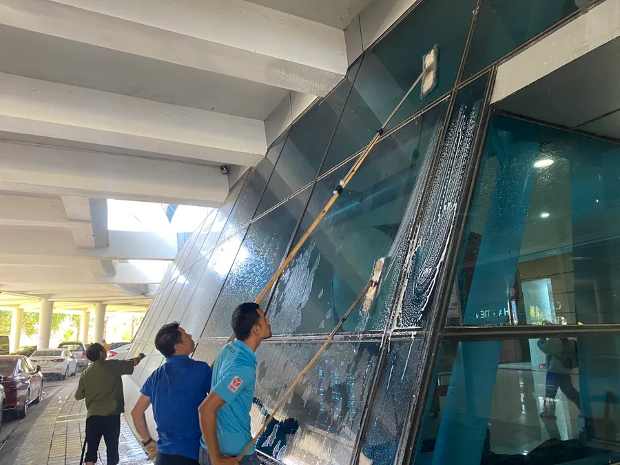 Nhân viên đang lau chùi toàn bộ cửa kính ở Cung Thể thao Tiên Sơn chuẩn bị cho Đại hội Thể thao học sinh Đông Nam Á. 
