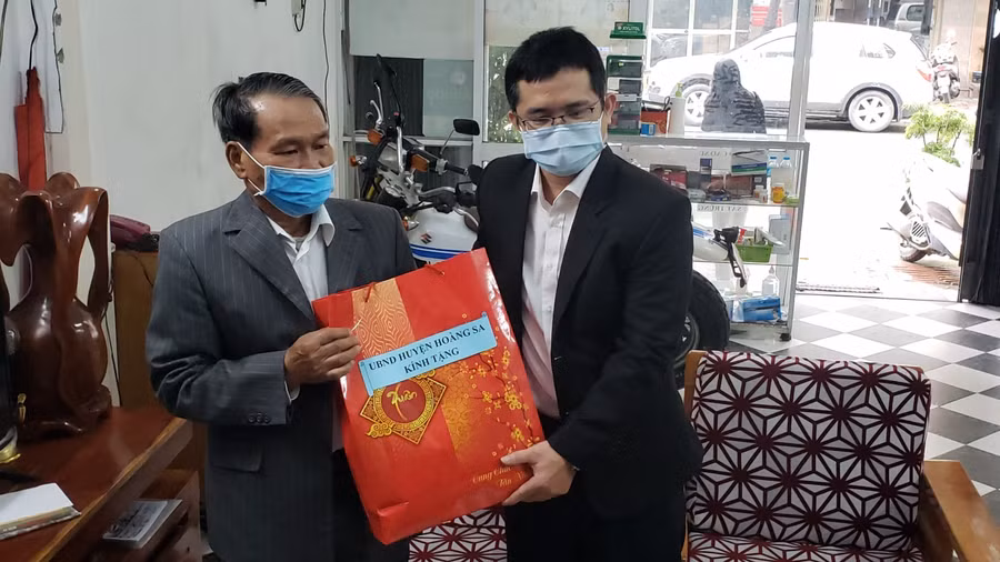 Đại diện lãnh đạo UBND huyện Hoàng Sa (TP Đà Nẵng) thăm và tặng quà cho ông Lê Đình Rê (bên trái). 