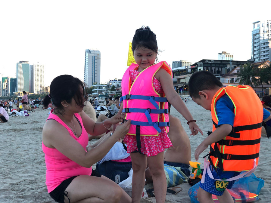 Các em nhỏ được mẹ trang bị áo phao trước khi xuống biển. Các em nhỏ được mẹ trang bị áo phao trước khi xuống biển.