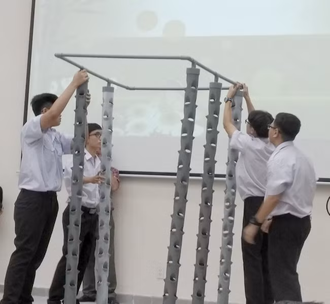 Các học sinh đang thực hiện lại quy trình làm hệ thống trồng cây khí canh trụ đứng của dự án "Cải tạo chất lượng không khí ở hầm xe" trong buổi báo cáo dự án.