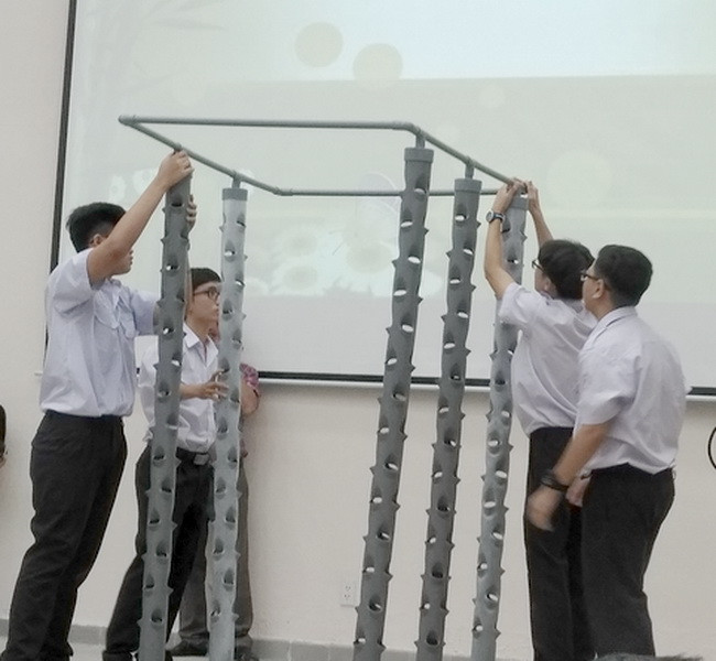 Các học sinh đang thực hiện lại quy trình làm hệ thống trồng cây khí canh trụ đứng của dự án "Cải tạo chất lượng không khí ở hầm xe" trong buổi báo cáo dự án.
