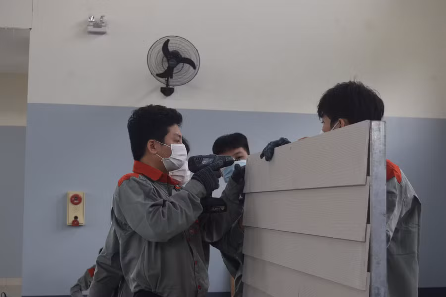 Các thí sinh thực hiện bài thi đóng ghép các tấm vách ngăn tường. Các thí sinh thực hiện bài thi đóng ghép các tấm vách ngăn tường.