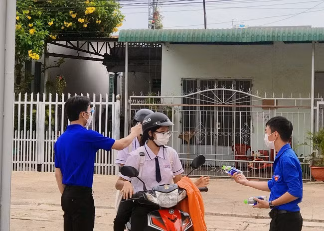 Lực lượng tình nguyện hỗ trợ đo thân nhiệt và phát nước uống cho các thí sinh trước khi vào phòng thi