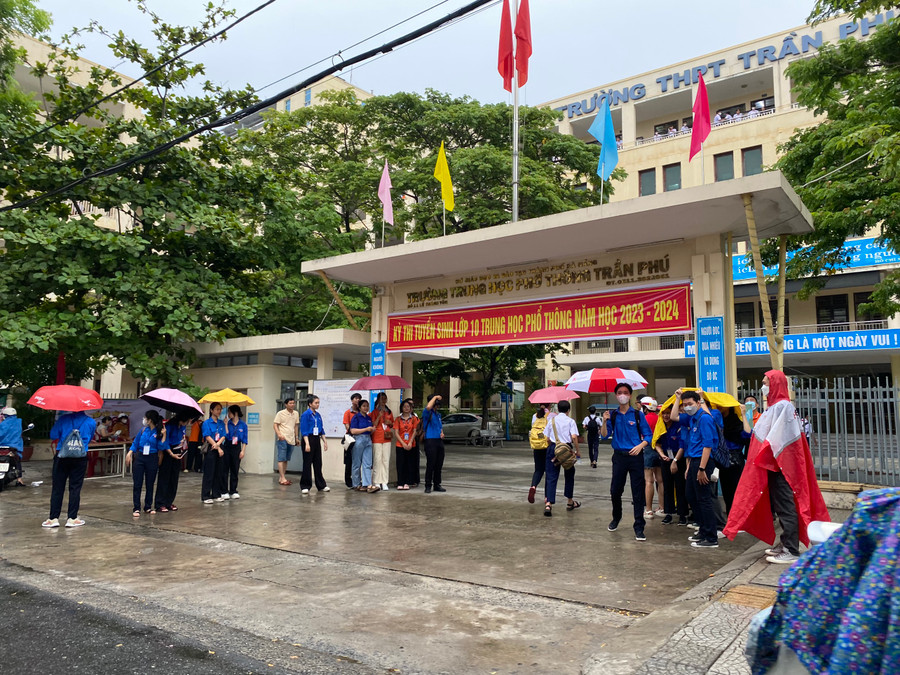 Đội tiếp sức mùa thi hỗ trợ nước uống và che dù cho thí sinh vào điểm thi. Ảnh: Hoàng Vinh.