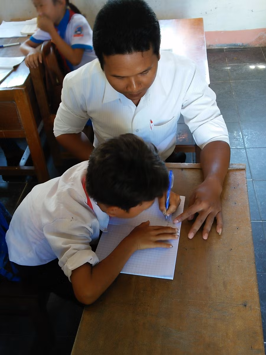 Thầy giáo Y Giêng đang chỉ cho học sinh viết chính tả.