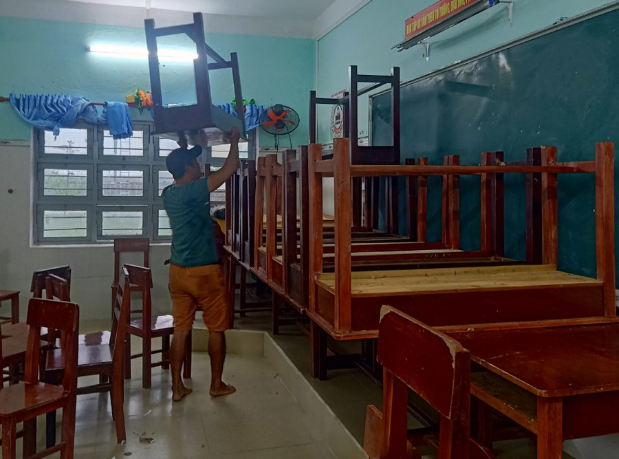 Thầy giáo đang kê cao bàn ghế để tránh nước lụt.