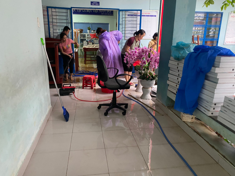 Thầy cô đang dọn dẹp trường lớp sau cơn mưa lớn.