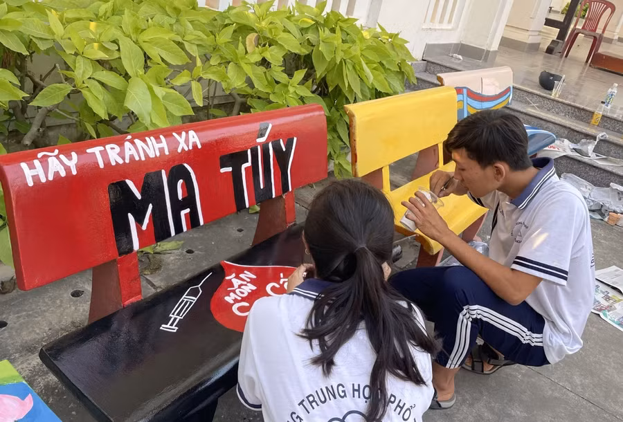 Học sinh vẽ thông điệp "hãy tránh xa ma túy" lên ghế đá (Ảnh: NTCC)