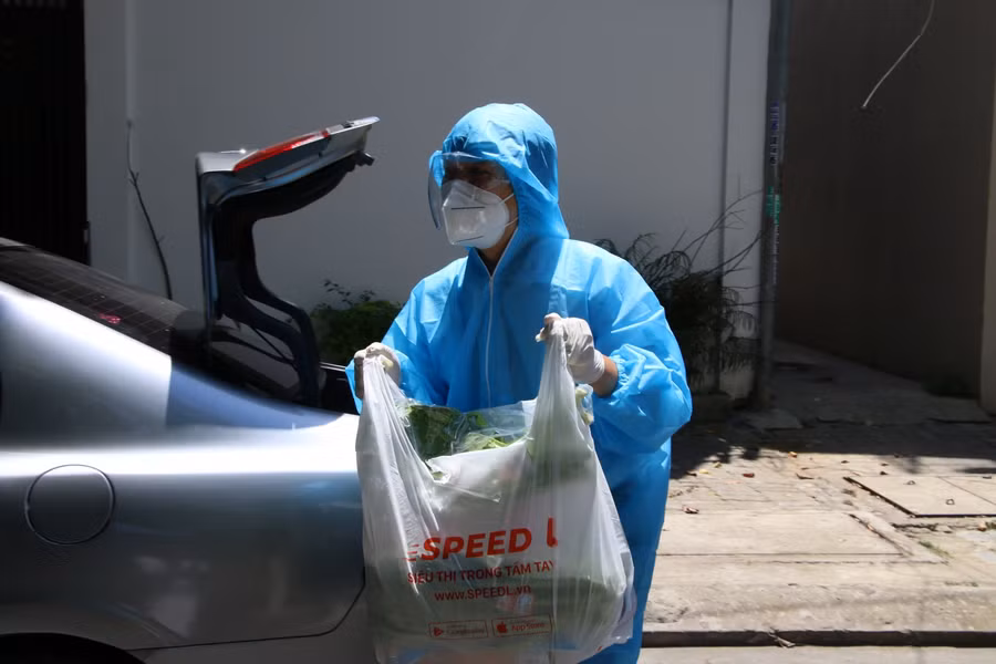 Các shipper trong trang phục bảo hộ khi đi giao hàng cho dân.
