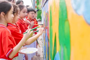Các em học sinh Trường Tiểu học Lê Văn Tám thể hiện bức tranh tường của mình.