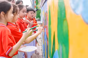 Các em học sinh Trường Tiểu học Lê Văn Tám thể hiện bức tranh tường của mình.