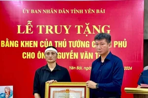 Ông Trần Huy Tuấn, Chủ tịch UBND tỉnh Yên Bái trao Bằng khen của Thủ tướng cho đại diện gia đình ông Nguyễn Văn Thi.