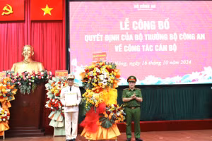 Thứ trưởng Bộ Công an Nguyễn Văn Long trao quyết định và tặng hoa chúc mừng Đại tá Hồ Song Ân. (Ảnh: TT)