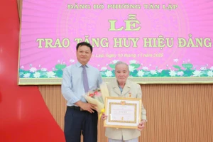 Ông Vũ Văn Hưng trao Huy hiệu 65 năm tuổi Đảng cho đảng viên Hà Học Tuấn. (Ảnh: Thành Tâm)
