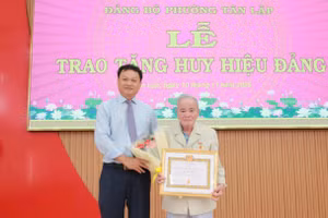 Ông Vũ Văn Hưng trao Huy hiệu 65 năm tuổi Đảng cho đảng viên Hà Học Tuấn. (Ảnh: Thành Tâm)