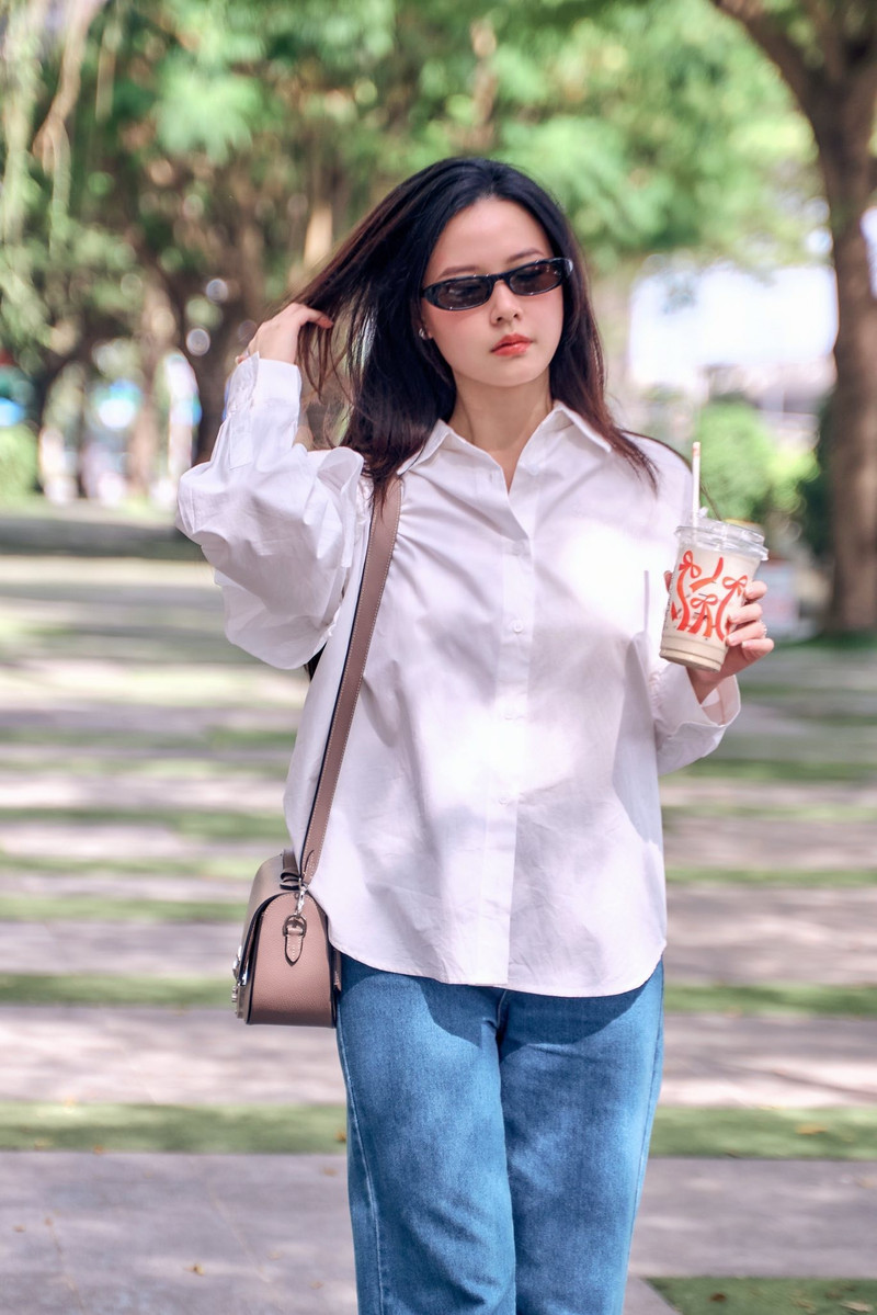 Sơ mi trắng dáng basic giúp tôn lên nét tinh khôi đặc trưng của cô, trong khi chiếc quần jeans đơn giản mang lại sự năng động và thoải mái. midu-1.jpg