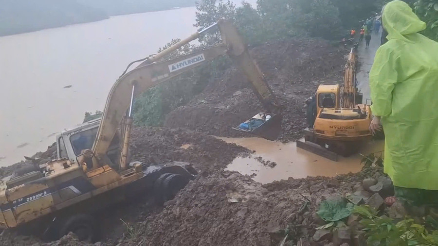 Xe múc đưa giáo viên qua khu vực sạt lở đến đến trường. 