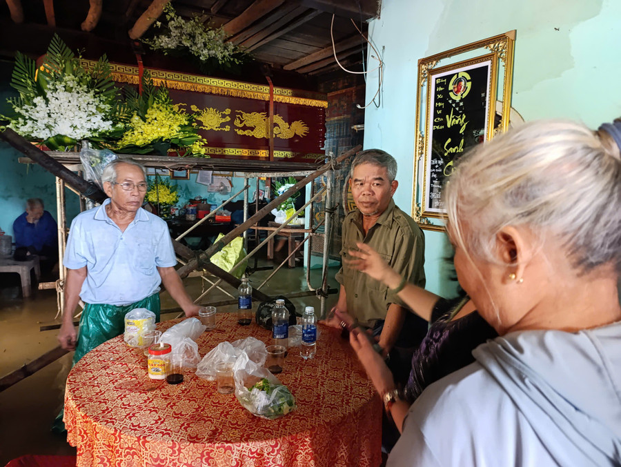 Ông Minh (bên trái) vận động người thân sớm đưa linh cữu cụ Đối đi an táng do nước sông dâng cao gây ngập lụt. 9bf7f0e52746aa18f357.jpg