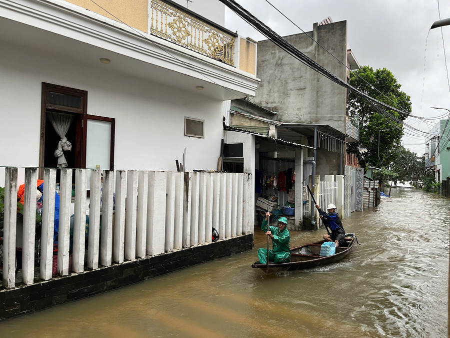 Ông Minh (áo mưa xanh) trên chiếc ghe nhỏ chèo đi khắp xóm để hỗ trợ người dân. 996066625430552711-1.jpg