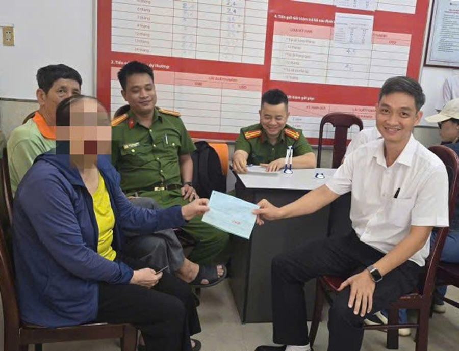 Lực lượng Công an và nhân viên ngân hàng làm thủ tục trao tiền lại cho bà P. Ảnh: CACC