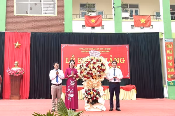 Ông Ngô Đức Sáu - Phó Bí thư Đảng ủy, Chủ tịch UBND xã Bản Nguyên (bên phải) tặng hoa chúc mừng thầy và trò nhà trường.