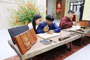 Các nghệ nhân hướng dẫn kỹ thuật in dập mộc bản - Ảnh: BTC.