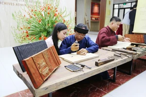 Các nghệ nhân hướng dẫn kỹ thuật in dập mộc bản - Ảnh: BTC.