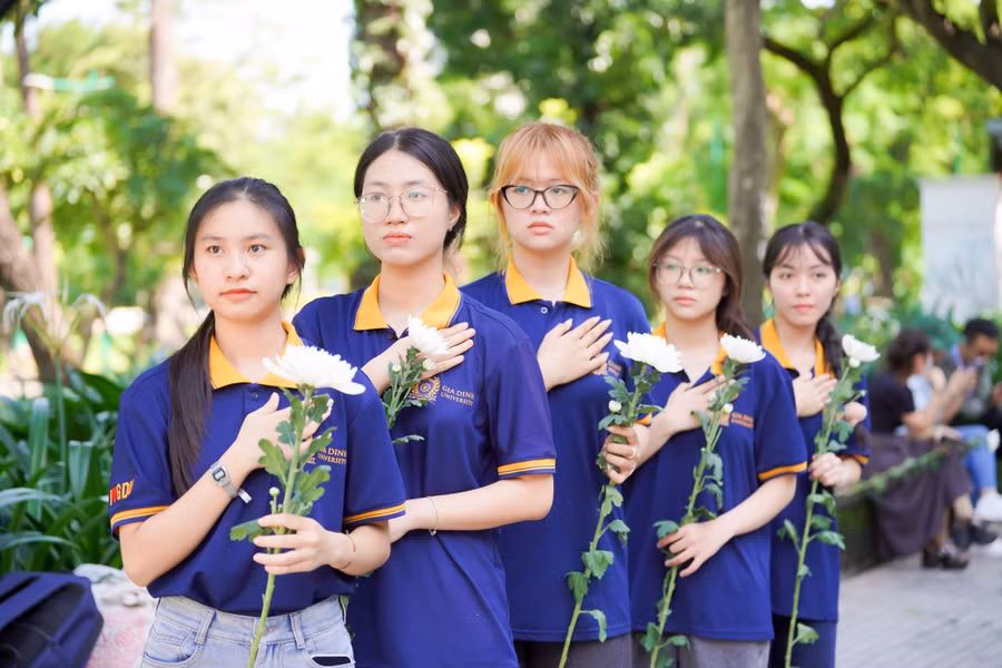 Sinh viên Trường Đại học Gia Định tay cầm hoa cúc trắng đặt tay lên ngực tiễn đưa các anh hùng liệt sĩ. Ảnh: GDU.
