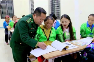 Cán bộ Đồn Biên phòng Quang Chiểu dạy chữ cho phụ nữ ở bản Pù Đứa. Ảnh: Thao Văn Chứ