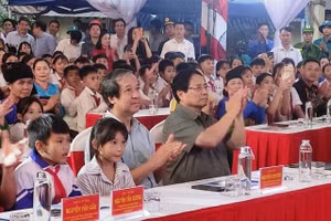 Thủ tướng Phạm Minh Chính và Bộ trưởng Bộ GD&ĐT Nguyễn Kim Sơn mời học sinh ngồi cạnh trong Lễ khởi công Trường phổ thông nội trú liên cấp Bát Mọt (Thanh Hóa). Ảnh: Thế Lượng