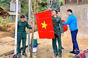 Các chiến sĩ Đồn Biên phòng Cửa khẩu Quốc tế Na Mèo (Thanh Hóa) giúp người dân cắm cờ Tổ quốc.