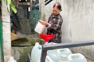 Giữa trưa, bà Trương Thị Hằng mang gàu vét chút nước còn sót lại ở chiếc giếng nước ngọt duy nhất của làng.