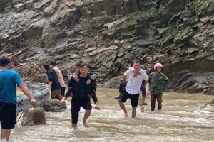 Thầy Nguyễn Chí Anh (áo sáng) cõng từng em học sinh qua dòng nước lũ ngập sâu để đón các em về trường an toàn sau bão số 3.