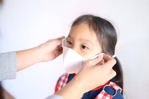 Để phòng bệnh, cha mẹ cần khuyến khích trẻ đeo khẩu trang ở nơi công cộng. Ảnh minh họa: INT