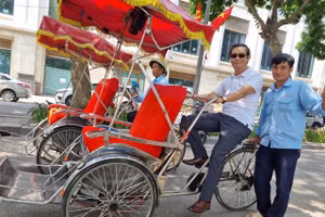 Anh xích lô tên Tiến ở phố cổ Hà Nội giúp tác giả Nguyễn Vân Hậu (ngồi trên xich lô) tìm lại ký ức năm xưa. Ảnh: NVCC.