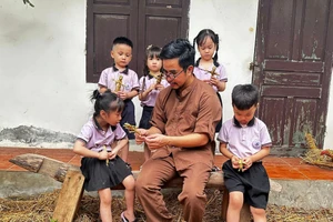 Nghệ nhân Nguyễn Tấn Phát hướng dẫn các em nhỏ làm hình nộm từ rơm.