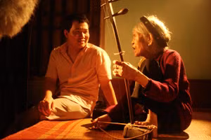 Đạo diễn Lương Đình Dũng trò chuyện cùng nghệ nhân Hà Thị Cầu trong phim 'Xẩm đỏ'. Ảnh cắt từ phim.