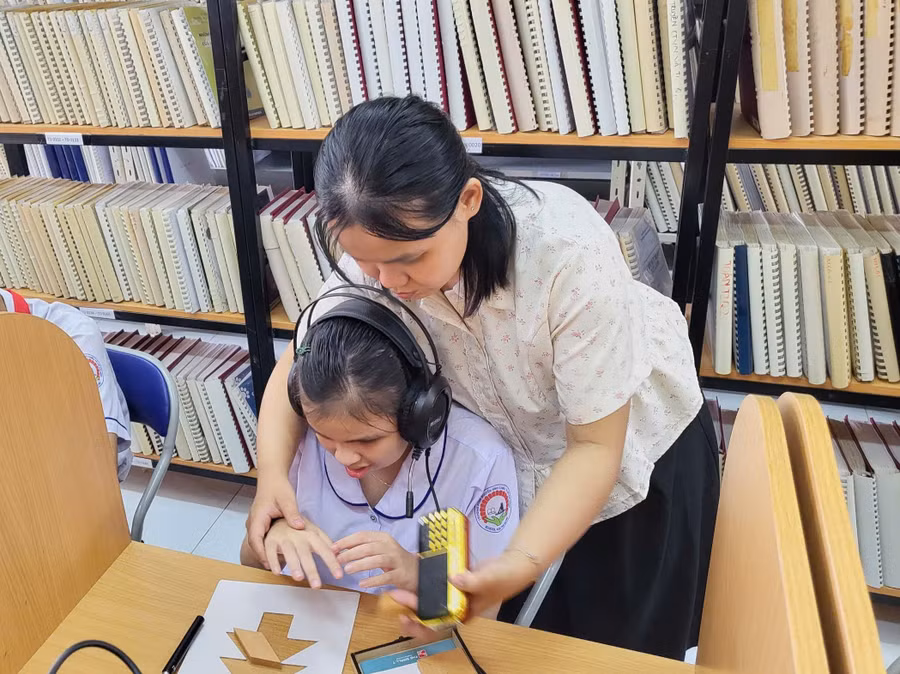 Cô giáo hướng dẫn cho học sinh tại thư viện của Trường PTĐB Nguyễn Đình Chiểu.