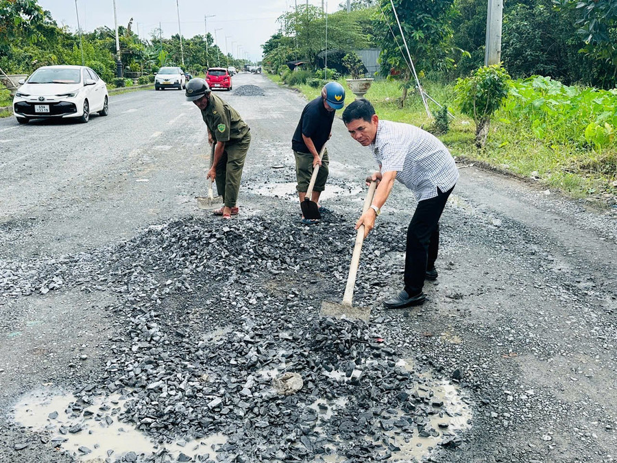 Ông Lê Bá Toàn (áo sơ mi) cùng lực lượng dân quân trong khu vực vá đường Nguyễn Văn Cừ.