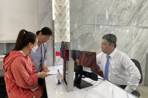 Công chức Võ Thanh Phát tại Trung tâm phục vụ hành chính công phường Sài Gòn hướng dẫn thủ tục cho người dân sáng 1/7. (Ảnh: Hà An)