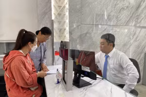 Công chức Võ Thanh Phát tại Trung tâm phục vụ hành chính công phường Sài Gòn hướng dẫn thủ tục cho người dân sáng 1/7. (Ảnh: Hà An)