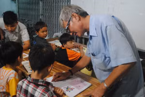 Ông Đoàn Minh Hùng chỉ bài cho học sinh tại lớp học tình thương. Ảnh: Phúc Uyên.