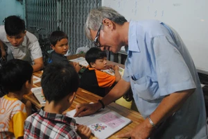Ông Đoàn Minh Hùng chỉ bài cho học sinh tại lớp học tình thương. Ảnh: Phúc Uyên.